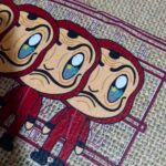 Exemplo de aplicação de arte que utiliza o pó TPU para DTF: imagem de três bonecos com macacão vermelho e máscara de Salvador Dali