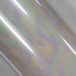 Foil furta-cor parcialmente desenrolado, com textura brilhante e reflexos multicoloridos, formando manchas suaves em um padrão ondulado.